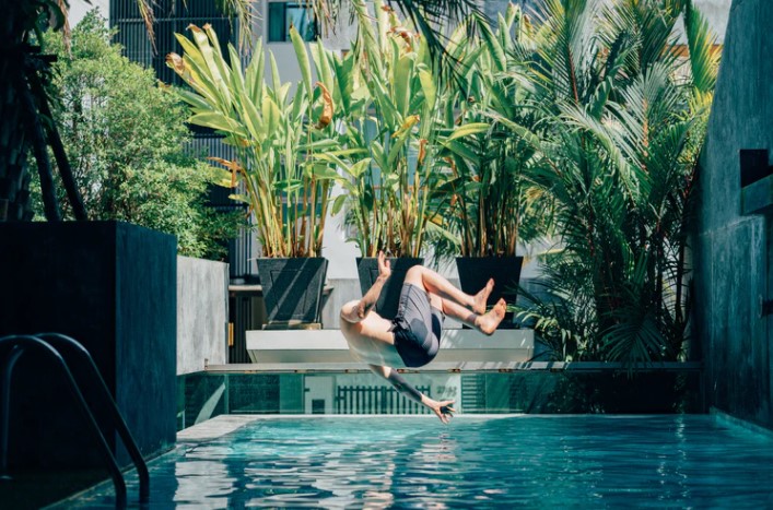 Person doing a backflip before diving into a plunge pool